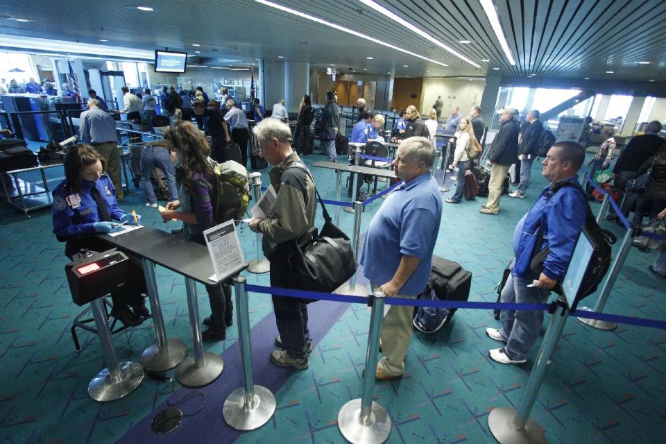 In this April 30, 2012, photo shows travelers passing through the security check point at Portland International Airport, in Portland, Ore. Airport security procedures, with their intrusive pat downs and body scans, don’t need to be toughened despite the discovery of a new al-Qaida airline bomb plot using more sophisticated technology than an earlier attempt, congressional and security officials said Tuesday. (AP Photo/Rick Bowmer)