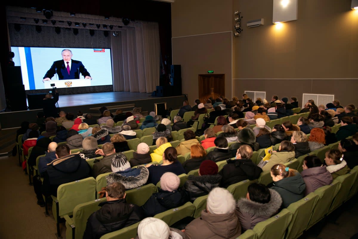 Residents in Russian-controlled Luhansk, eastern Ukraine, watching Putin speak on Tuesday (AP)