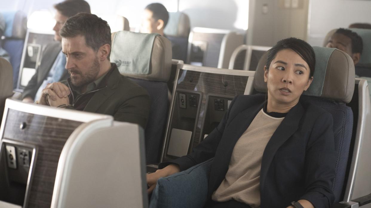  Dr Matthew Nolan (Richard Armitage), in handcuffs, sits alongside a panicked looking DC Hana Li (Jing Luci) aboard an passenger plane in Red Eye. 