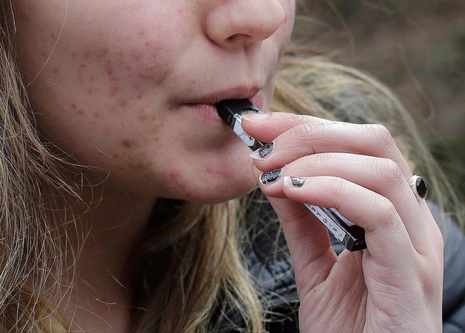 FILE - In this April 11, 2018, file photo, a high school student uses a vaping device near a school campus in Cambridge, Mass. California Gov. Gavin Newsom will announce an executive action Monday, Sept. 16, 2019, to confront youth heath concerns related to vaping.  (AP Photo/Steven Senne, File)