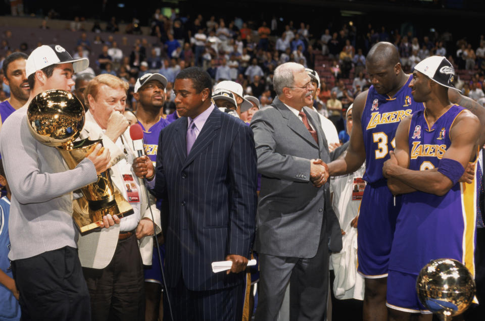 Head coach Phil Jackson of the Los Angeles Lakers congratulates guard Kobe Bryant #8 and center Shaquille O'Neal #34 as broadcaster Ahmad Rashad of NBC interviews Lakers owner Dr. Jerry Buss after Game Four of the 2002 NBA Finals against the New Jersey Nets at Continental Airlines Arena in East Rutherford, New Jersey on June 12, 2002. The Lakers defeated the Nets 113-107 and won the series 4-0. (Photo by Noren Trotman/NBAE/Getty Images)