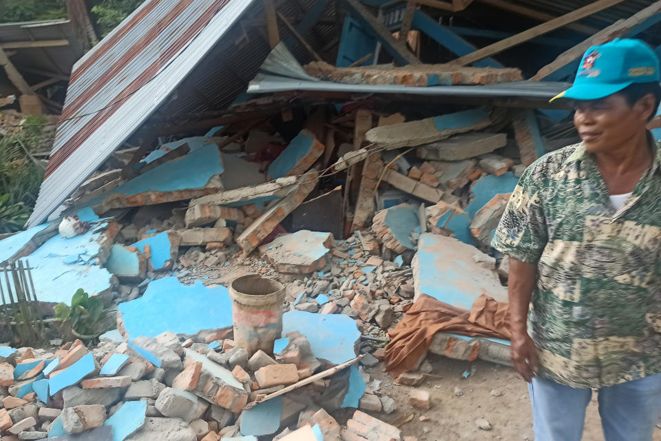 A man stands near a damaged house following an earthquake in Pasaman, West Sumatra, Indonesia, Friday, Feb. 25, 2022. The strong and shallow earthquake hit off the coast of Indonesia's Sumatra island on Friday, panicking people in Sumatra island and neighboring Malaysia and Singapore. (AP Photo/Marsulai)