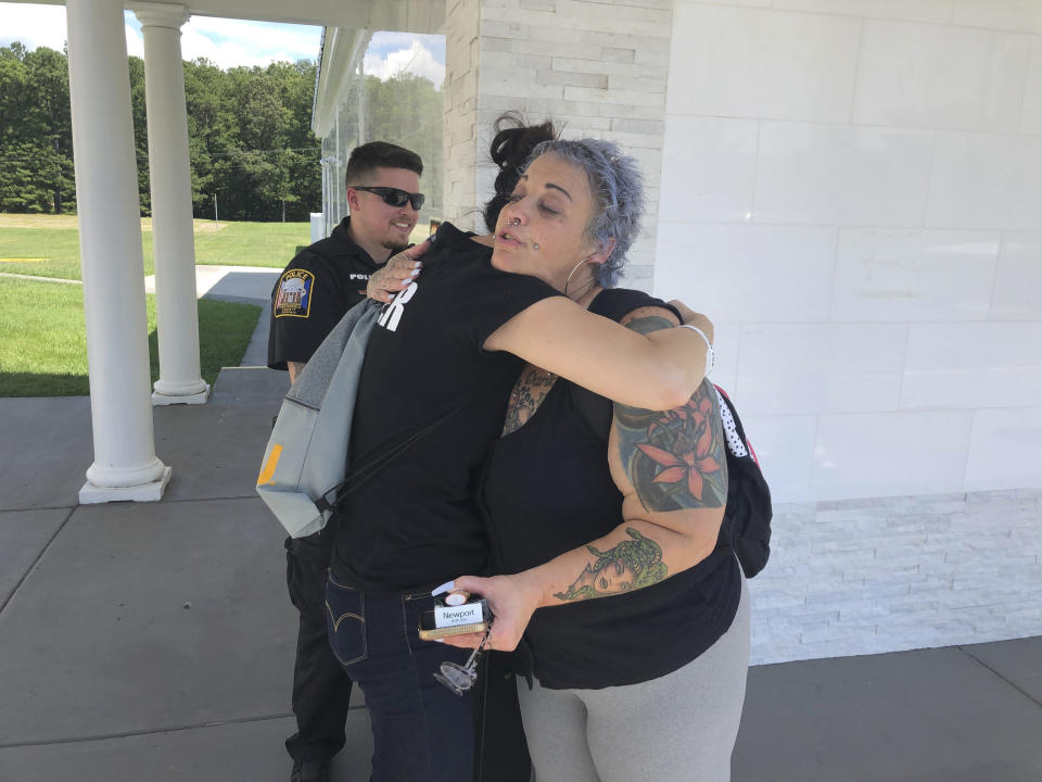 Chesterfield Patrol Officer Travis Adams, left, and peer recovery specialist Joy Bogese, center, hugs Rhonda Kanary while on patrol as part of Project Recover, in Chesterfield County, Va., Monday Aug., 29, 2022. Project Recover is a program that embeds recovering addicts with police and ambulance crews in central Virginia to respond to overdose calls and to go on patrol to reach out to people struggling with drug addiction to try to get them into treatment programs. (AP Photo/Denise Lavoie)