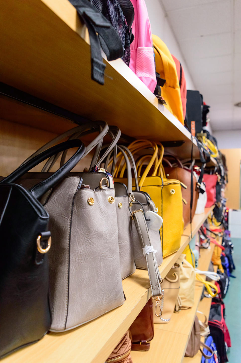 Shelves filled with various handbags in different styles and sizes, organized neatly in a store