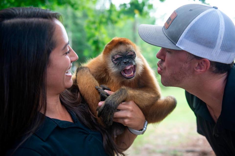 Bre Anderson, staff manager at Wild Acres, and Cody Breland, owner of Wild Acres, make faces with Kiki, a spider monkey, outside his enclosure at Wild Acres in McHenry on Thursday, July 6, 2023.