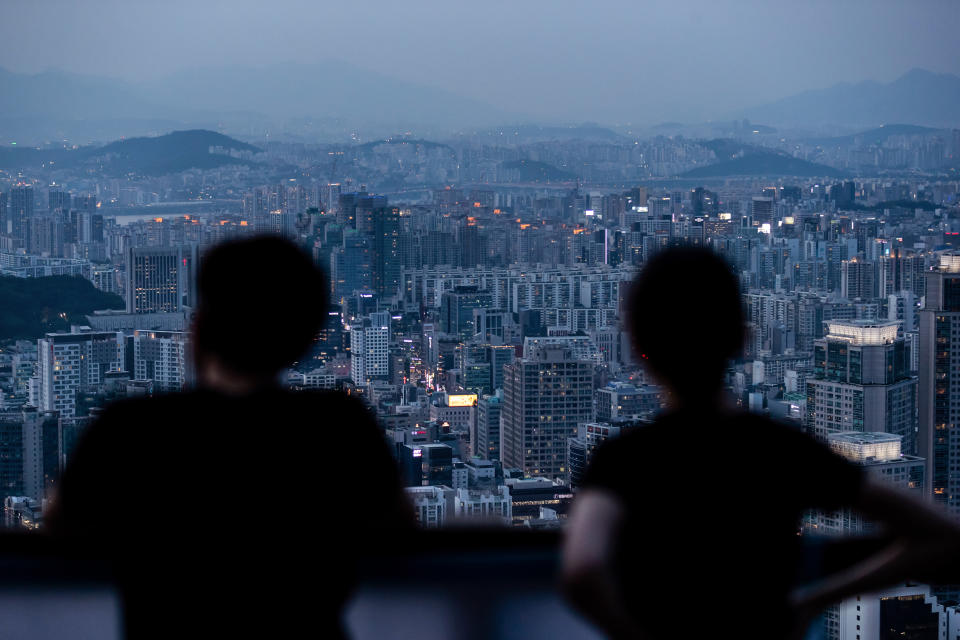 People look at a city skyline from an observation deck of Woomyeon mountain at dusk in Seoul, South Korea, on July 9, 2020. (SeongJoon Cho / Bloomberg via Getty Images file)