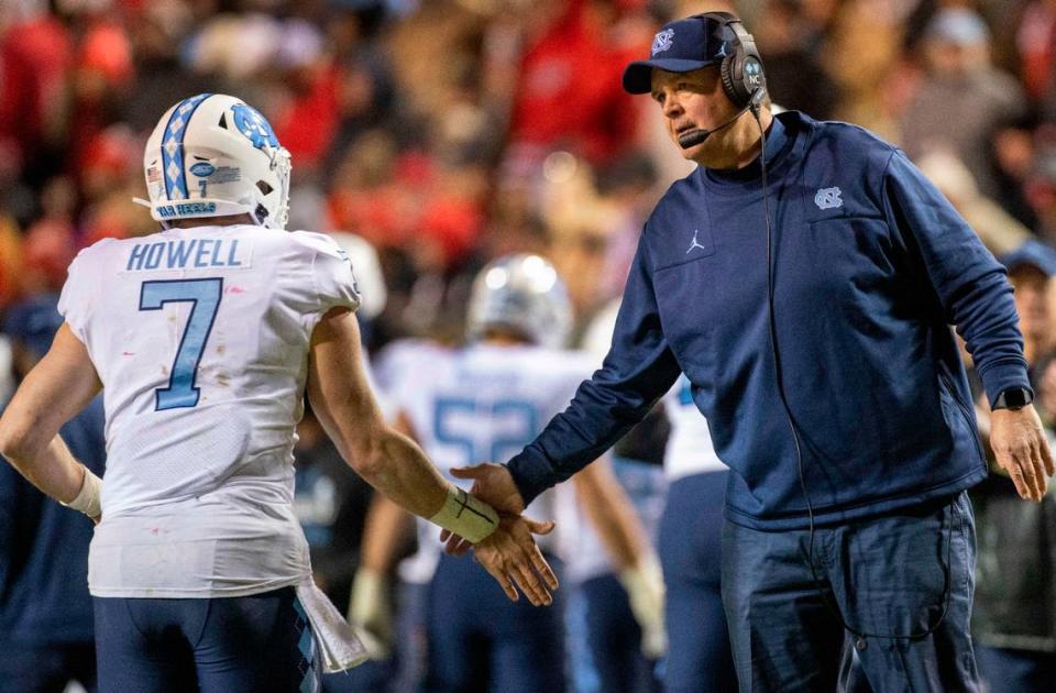 North Carolina offensive line coach Stacy Searles congratulates North Carolina quarterback Sam Howell after scoring to put the Tar Heels up 24-14 over N.C State in the third quarter on Friday, November 26, 2021 at Carter-Finley Stadium in Raleigh, N.C.