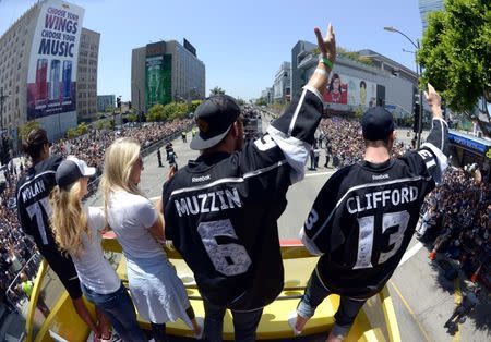 Los Angeles Kings players Jordan Nolan (74) , Jake Muzzin (6) and Kyle Clifford (13) with Lauren Nolan and Courtney Fischer wave to the crowd during a parade on Figueroa Street to celebrate winning the 2014 Stanley Cup. Mandatory Credit: Kirby Lee-USA TODAY Sports