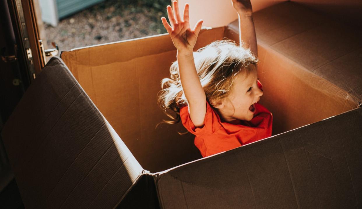 An image of a girl playing in a cardboard box.