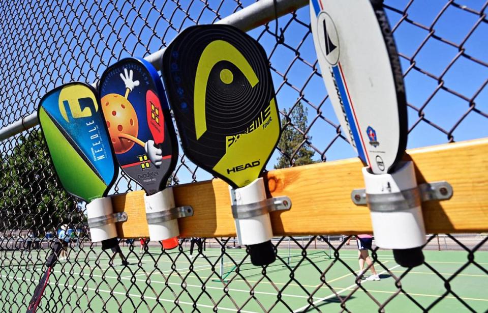 Pickleball paddles are positioned in order of court access as pickleball enthusiasts play at Rotary East Park Wednesday morning, June 21, 2023 in Fresno.