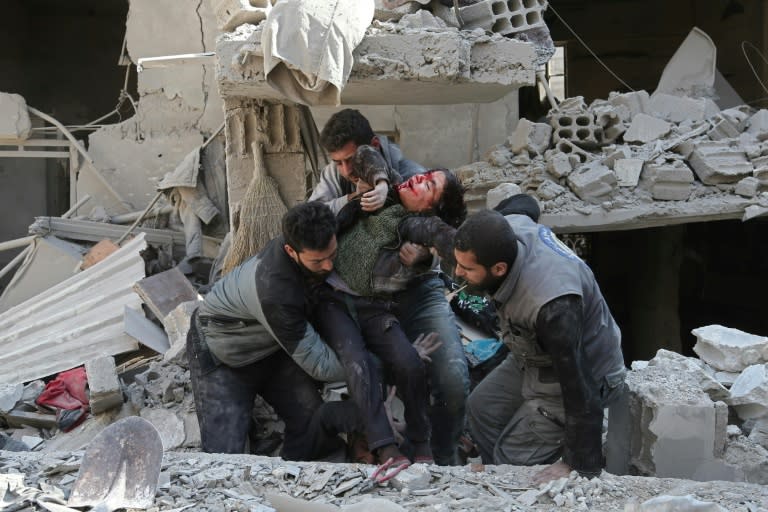 Syrians rescue a child after a reported regime air strike in the rebel-held town of Hammuriyeh in the besieged Eastern Ghouta region outside Damascus on February 21, 2018