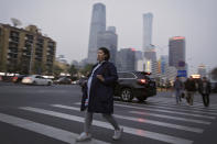 In this Wednesday, April 17, 2019, photo, a pregnant woman walks across a road near the Central Business District during the evening rush hour in Beijing. Remarks by the head of Chinese online business giant Alibaba, Ma Jack, one of China's richest men, that young people should work 12-hour days, six days a week if they want financial success have prompted a public debate over work-life balance in the country. Online complaints included blaming long work hours for a lower birth rate in the country. (AP Photo/Andy Wong)