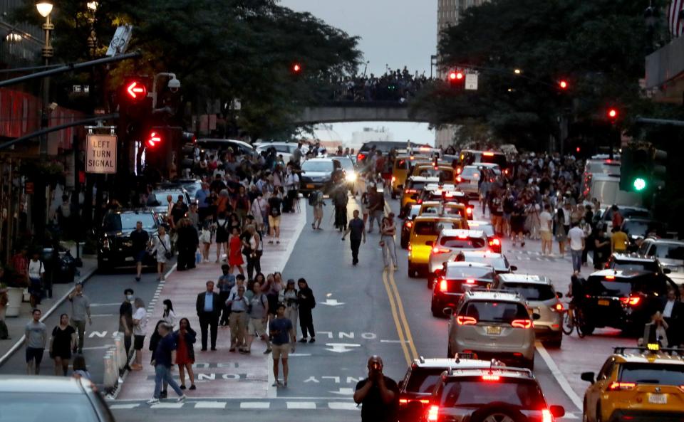 Pedestrians stop traffic on 42nd St. in Manhattan July 11, 2022 to photograph the phenomenon known as Manhattanhenge.