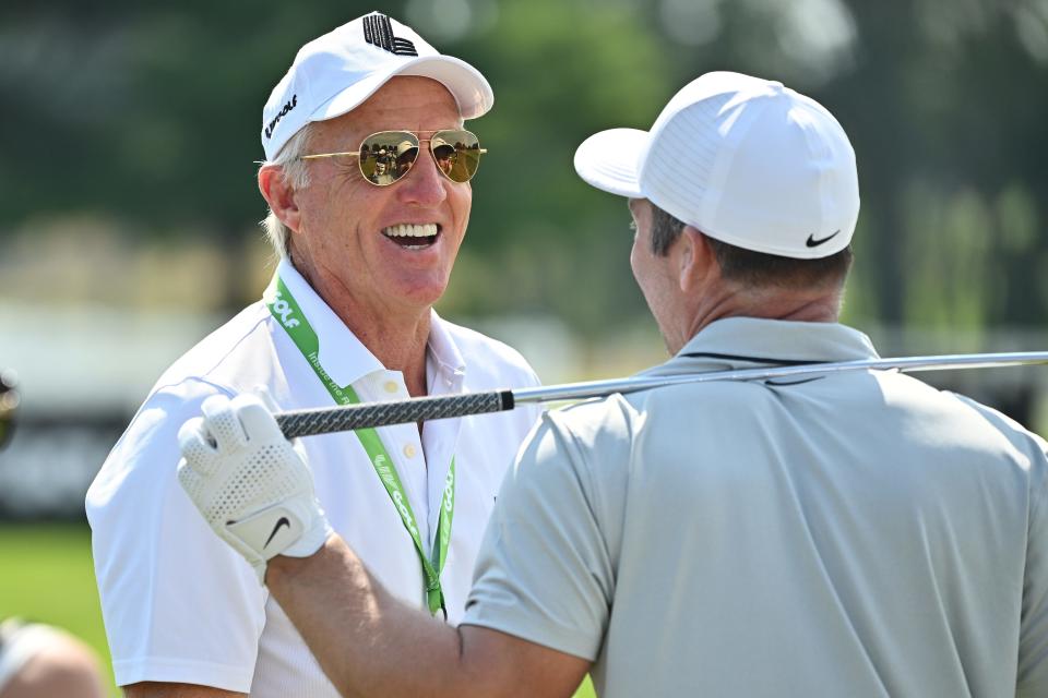 Greg Norman talks with Paul Casey on the driving range at a LIV Golf tournament.