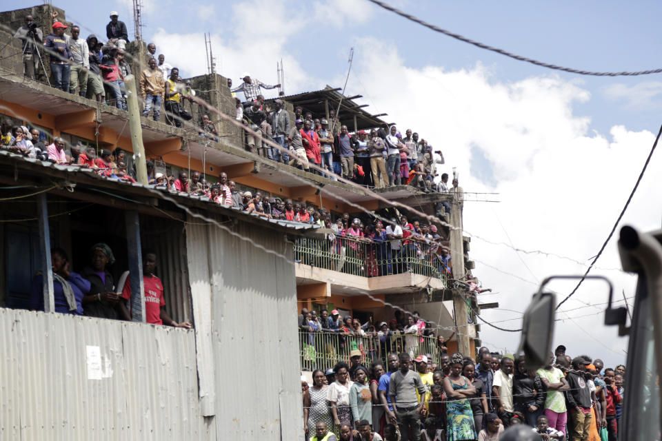 People watch as rescue workers attend the scene of a building that collapsed in Tasia Embakasi, an east neighbourhood of Nairobi, Kenya on Friday Dec. 6, 2019. A six-story building collapsed in Kenya's capital on Friday, officials said, with people feared to be trapped in the debris. Police say people have been rescued by residents using their bare hands. (AP Photo/Khalil Senosi)