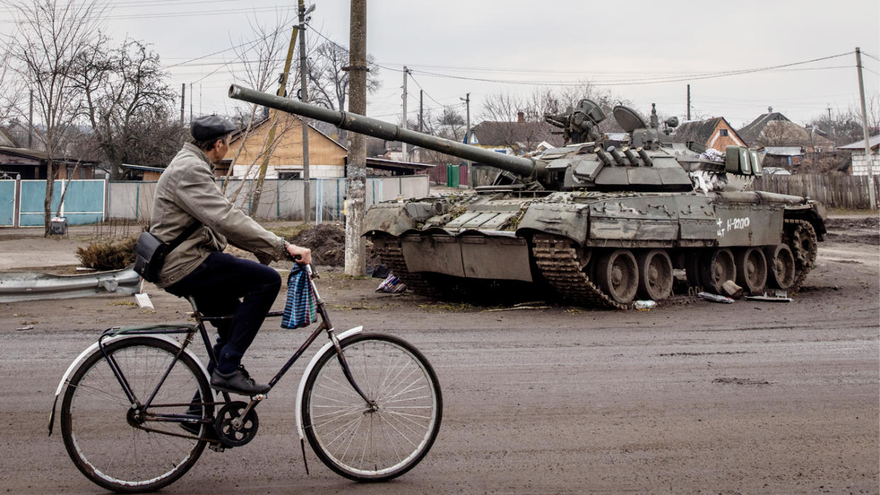 A man rides his bike past a destroyed Russian tank on March 30 in Trostyanets, Ukraine. 