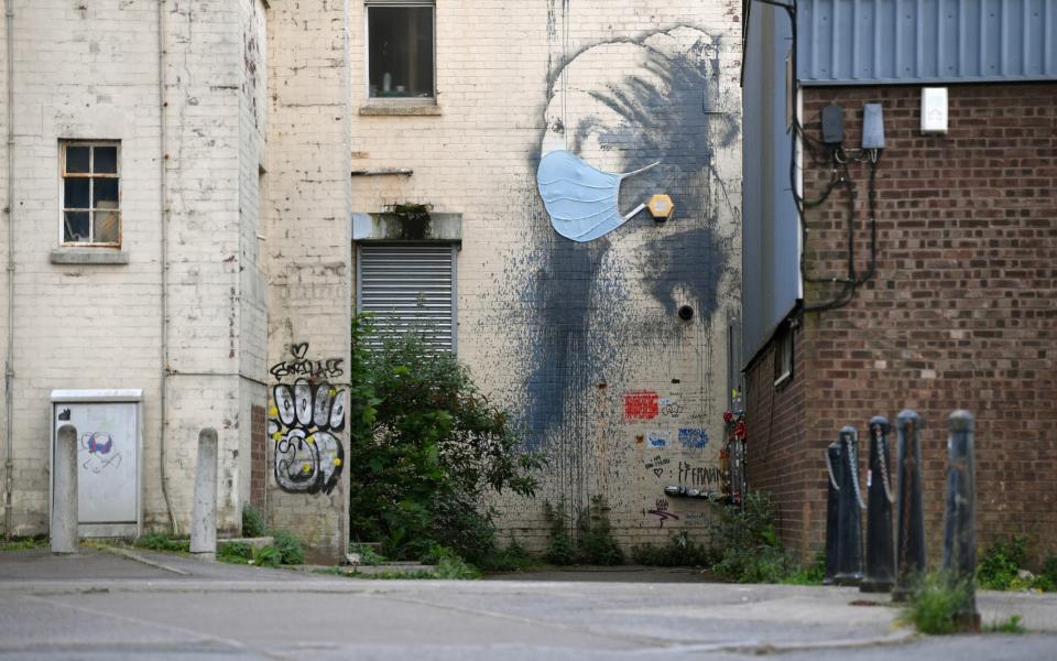 The graffiti artwork by Banksy named 'Girl with a Pierced Eardrum' is seen with a protective face mask at Hannover Place on April 27, 2020 in Bristol, England. British Prime Minister Boris Johnson, who returned to Downing Street this week after recovering from Covid-19, said the country needed to continue its lockdown measures to avoid a second spike in infections.  - Dan Mullan/Getty Images Europe