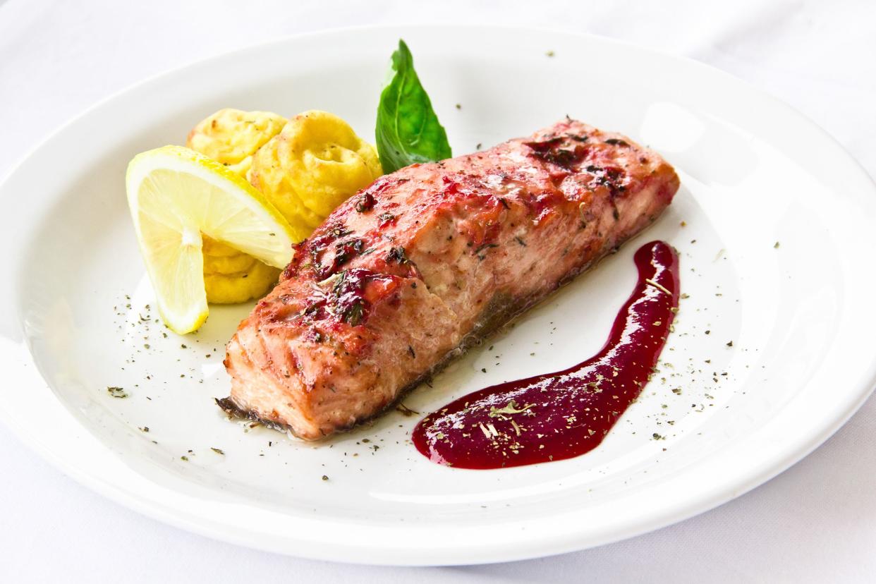 Thanksgiving salmon with red sauce and garnish on a white plate with a white background