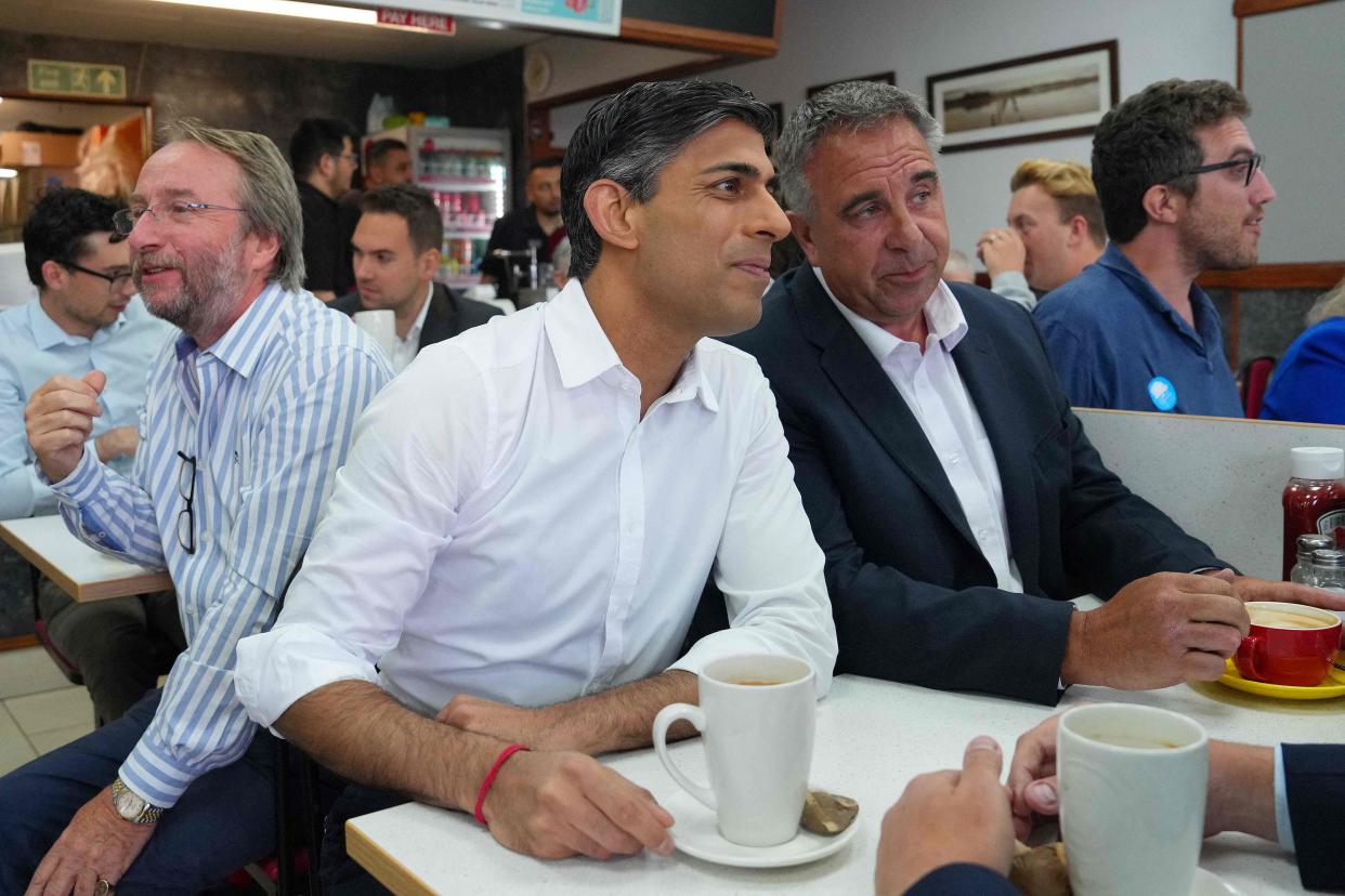 Britain's Prime Minister Rishi Sunak (C) sits with newly elected Conservative MP Steve Tuckwell (R) at a cafe in Ruislip (POOL/AFP via Getty Images)