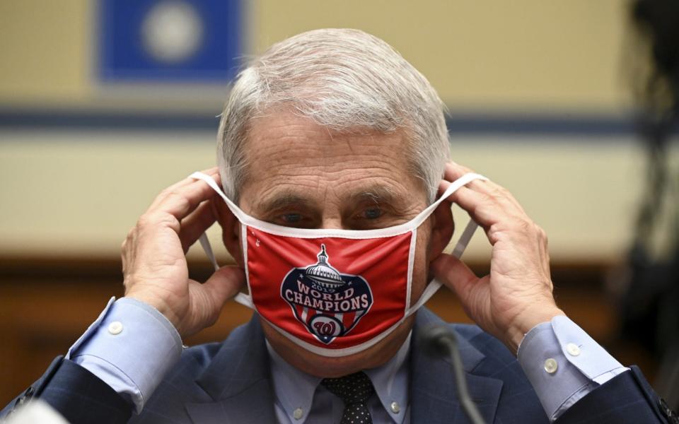 Anthony Fauci, director of the National Institute of Allergy and Infectious Diseases, removes his Washington Nationals protective mask during a Congress committee meeting on the coronavirus crisis  - Getty Images North America