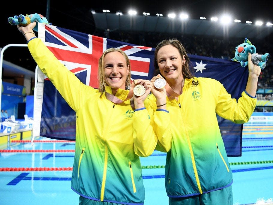 Swimmers Bronte and Cate Campbell hold an Australian flag after an event