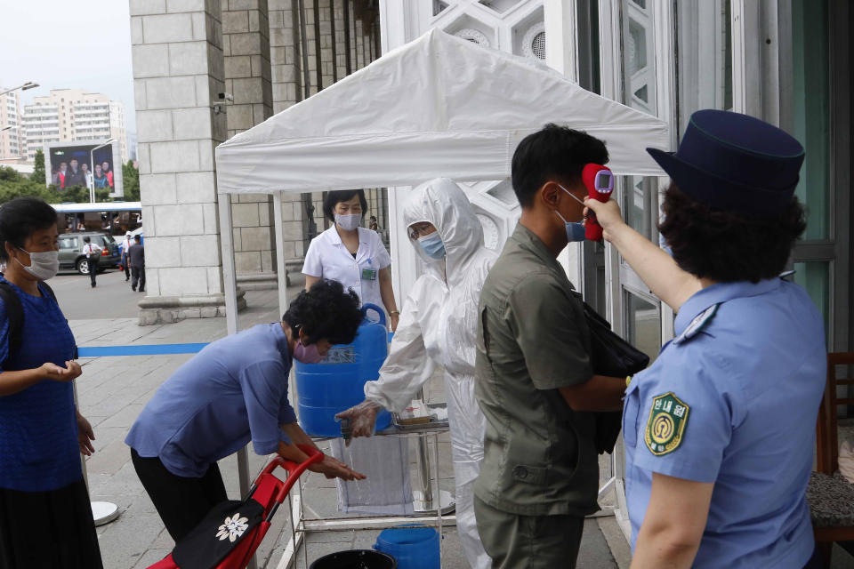 People are disinfected their hands and get fever checked before going into the Pyongyang Railway Station in Pyongyang, North Korea, Thursday, Aug. 13, 2020. (AP Photo/Cha Song Ho)