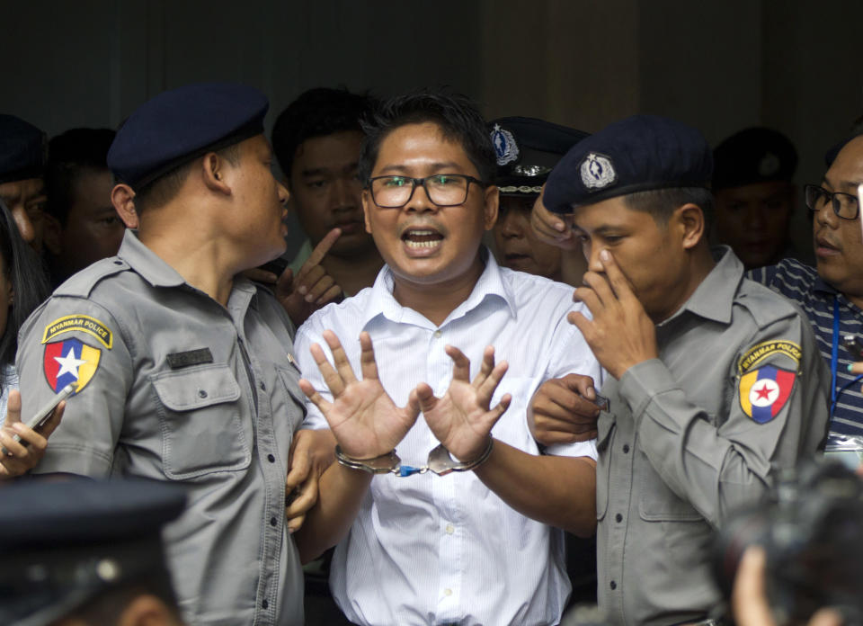 Reuters journalist Wa Lone, center, talks to journalists as he is escorted by police to leave a court in Yangon, Myanmar Monday, Sept. 3, 2018. The court in Myanmar has sentenced two Reuters journalists to seven years in prison for illegal possession of official documents, a ruling that comes as international criticism mounts over the military's alleged human rights abuses against Rohingya Muslims. (AP Photo/Thein Zaw)