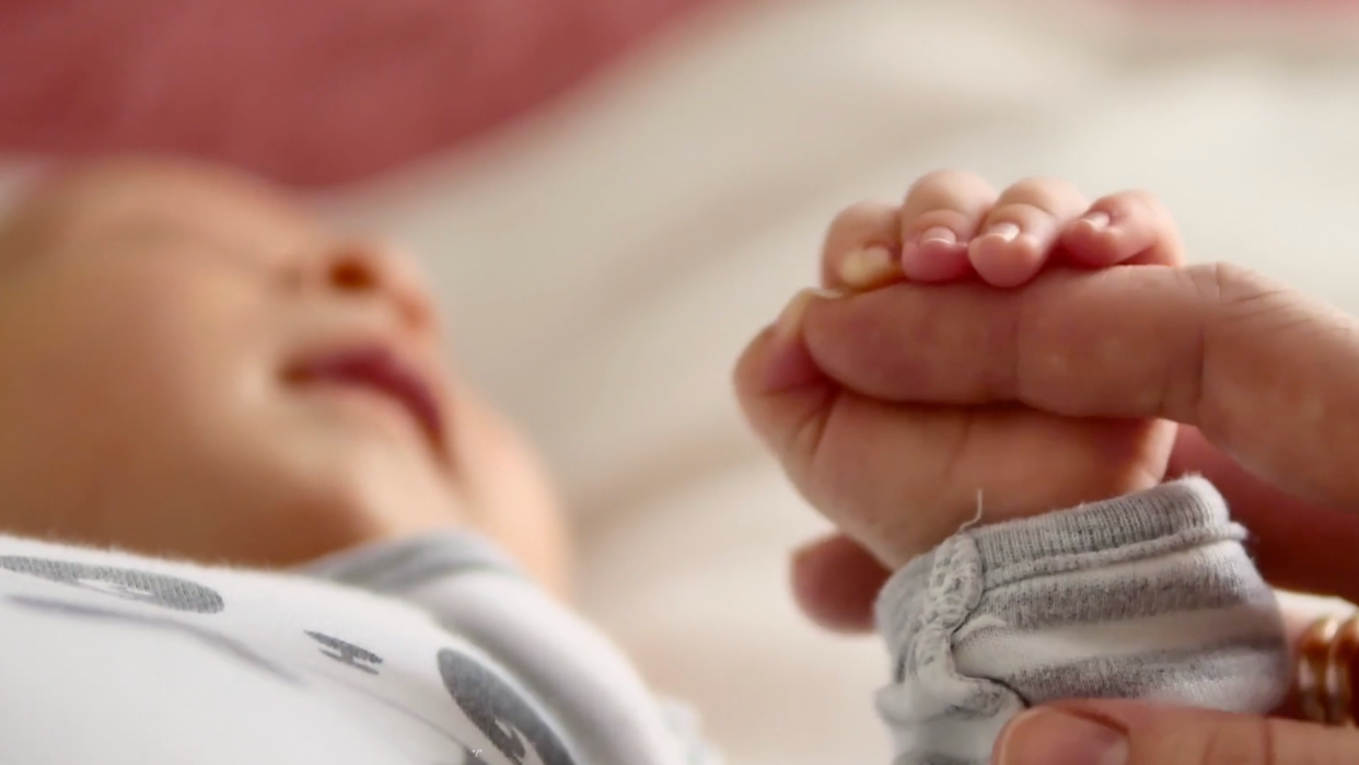 A baby grasping an adult finger.