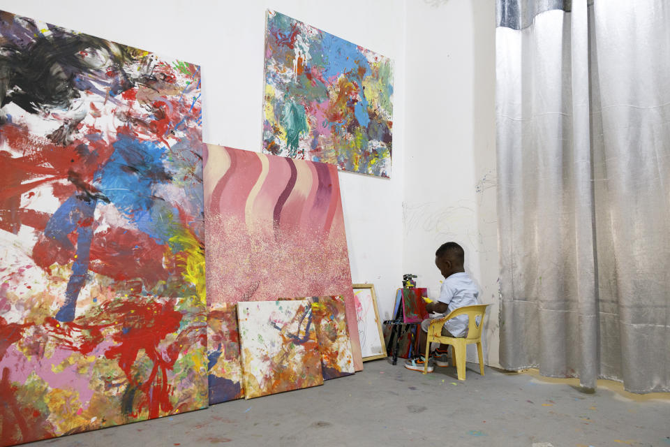 Ace-Liam Nana Sam Ankrah, who will turn two in July, paints amidst his own art work at his mother's art gallery in Accra, Ghana, Monday, May 27, 2024. Ankrah has set the record as the world's youngest male artist. His mother, Chantelle Kukua Eghan, says it all started by accident when her son, who at the time was 6 months old, discovered her paints. (AP Photo/Misper Apawu)