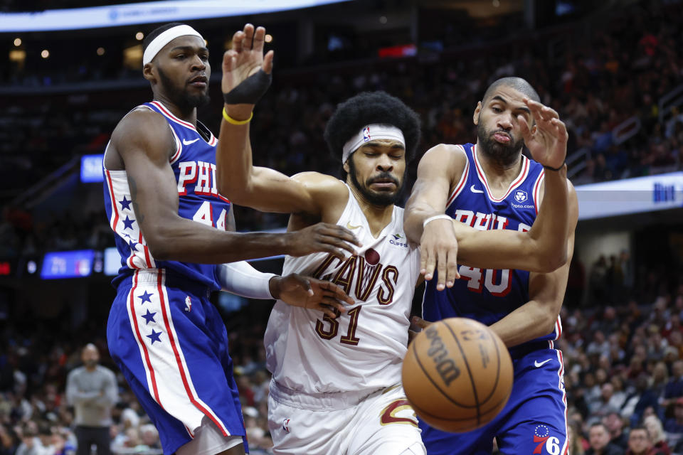 Cleveland Cavaliers center Jarrett Allen (31) and Philadelphia 76ers forward Paul Reed (44) and forward Nicolas Batum (40) try for a rebound during the second half of an NBA basketball game Friday, March 29, 2024, in Cleveland. (AP Photo/Ron Schwane)