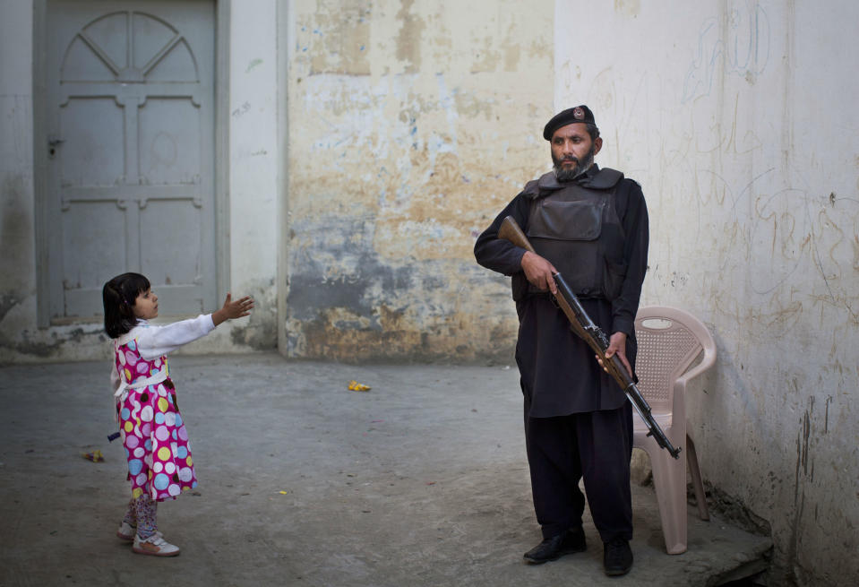 <p>Una niña se acerca a saludar a un policía que custodia la casa de Kainat Riaz, una amiga de Malala Yousafzai que también fue herida por los talibanes, en Mingora (Pakistán). (Foto: Anja Niedringhaus / AP). </p>