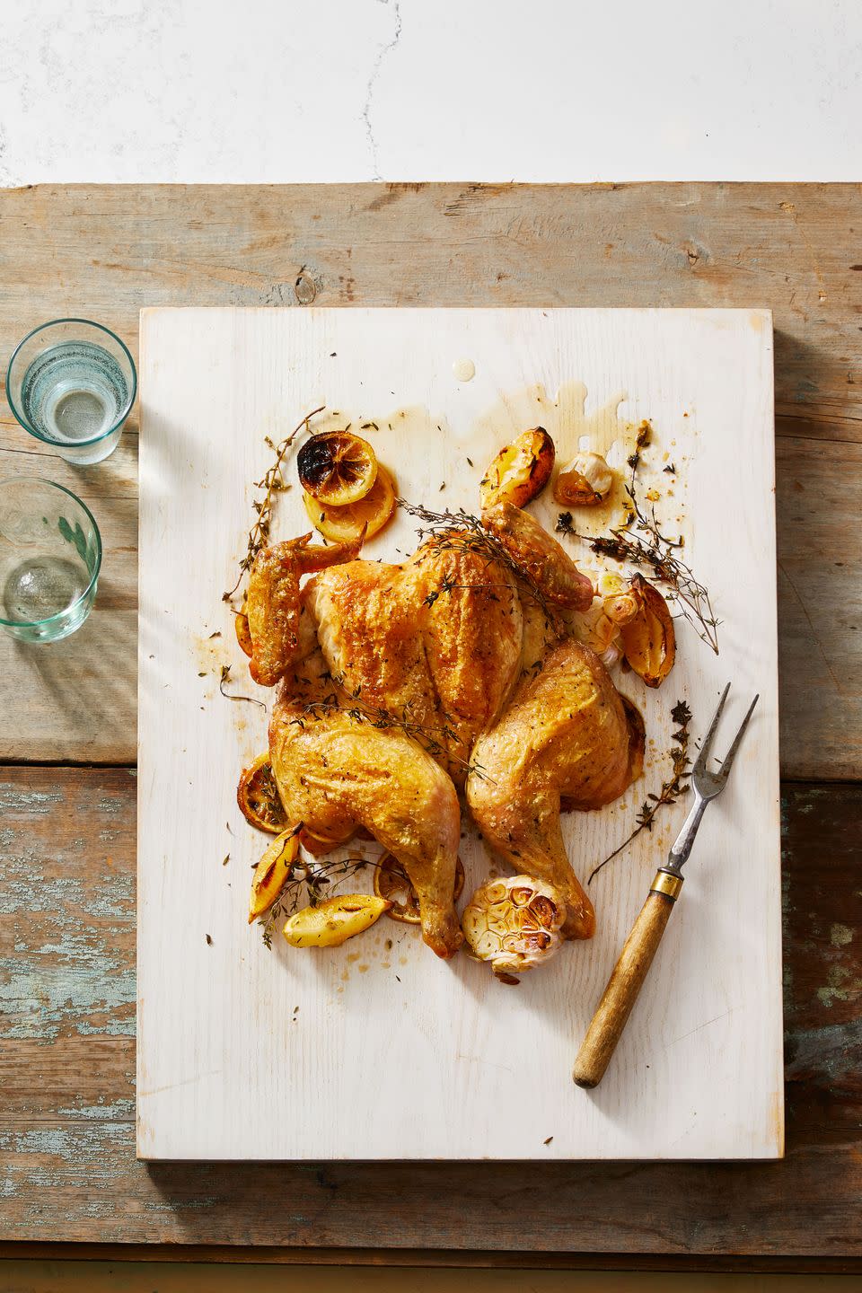 spatchcock chicken with lemon and garlic on a wooden board