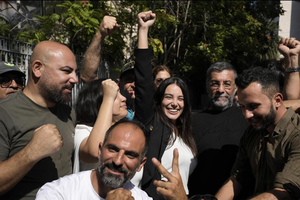 Sali Hafez, center, who broke into a BLOM Bank branch last month with others activists and forced bank employees to hand over $12,000 and the equivalent of about $1,000 in Lebanese pounds gestures as she leaves the Justice Palace, in Beirut, Lebanon, Thursday, Oct. 6, 2022. A Lebanese judge on Thursday fined and issued a six-month travel ban to Hafez who stormed her bank with a fake pistol and took her trapped savings to cover her sister's cancer treatment. (AP Photo/Hassan Ammar)