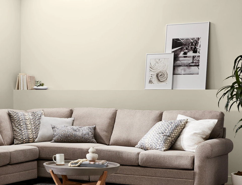 A subtly decorated living room with a beige sofa and walls painted with Valspar's Cream in My Coffee paint color.