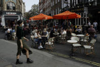People sit outside on a street closed to traffic to try to reduce the spread of coronavirus so bars, cafes and restaurants can continue to stay open, in the Soho area of central London, Saturday, Sept. 19, 2020. Fresh nationwide lockdown restrictions in England appear to be on the cards soon as the British government targeted more areas Friday in an attempt to suppress a sharp spike in new coronavirus infections. (AP Photo/Matt Dunham)
