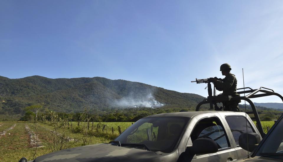 A Mexican soldier watches the horizon for cartel members after CJNG downed a military helicopter with a grenade in Villa Purificaciόn, Jalisco. The deadly 2015 attack was part of escalating violence during CJNG's power grab.