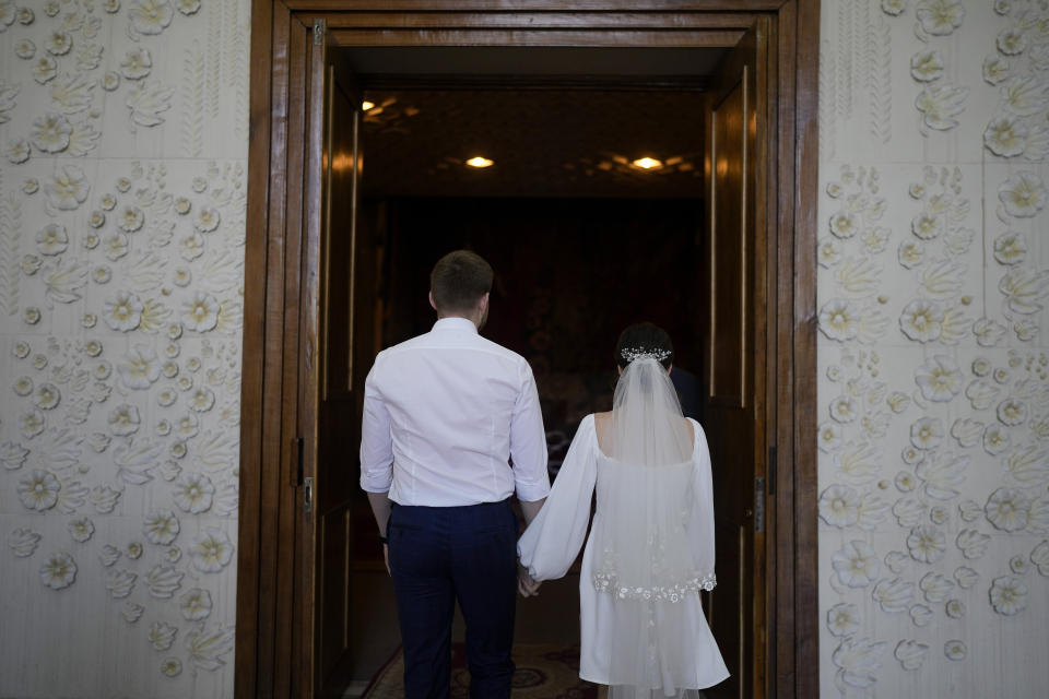 Kateryna Lytvynenko and Ihor Zakvatskyi enter to get married in Kyiv, Ukraine, Wednesday, June 15, 2022. Ihor proposed to Kateryna on the day the war started. A growing number of couples in Ukraine are speedily turning love into matrimony because of the war with Russia. Some are soldiers, marrying just before they head off to fight. Others are united in determination that living and loving to the full are more important than ever in the face of death and destruction. (AP Photo/Natacha Pisarenko)