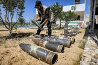 An explosives expert of Hamas lays out unexploded projectiles from the 11-day conflict with Israel last month, at a local police precinct in Khan Yunis in the southern Gaza Strip