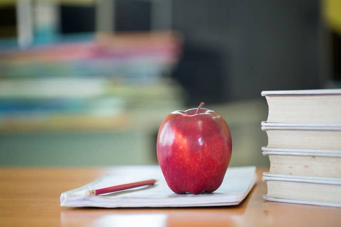 A school teacher's desk with stack of books and apple