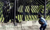 A member of the riot security forces points a gun through the fence at an opposition supporter during clashes at a rally against Venezuelan President Nicolas Maduro's government in Caracas, Venezuela June 22, 2017. REUTERS/Carlos Garcia Rawlins