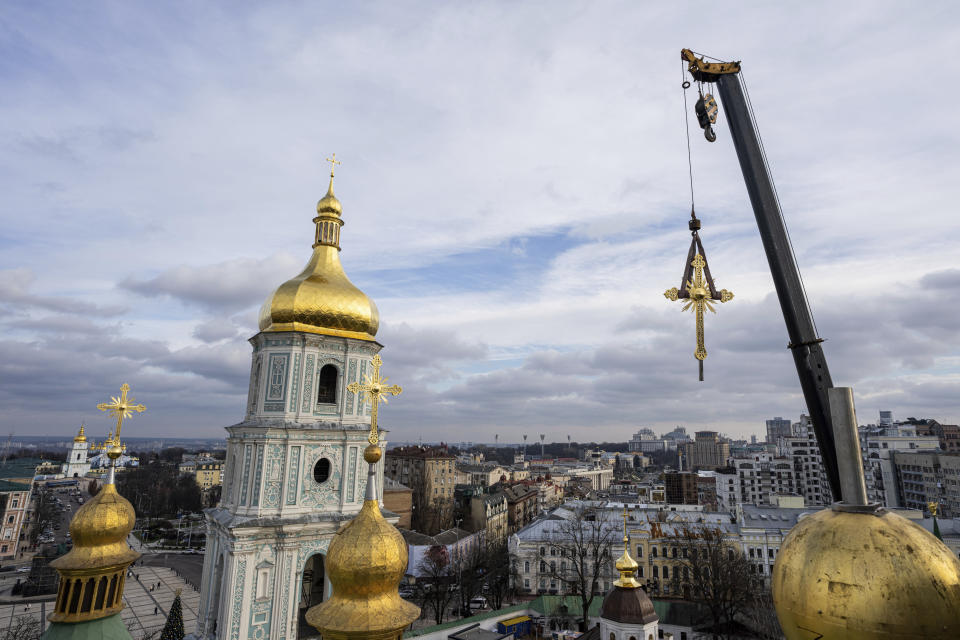 A crane lifts a cross before installing it on a dome of the Saint Sophia Cathedral in Kyiv, Ukraine, Thursday, Dec. 21, 2023. A UNESCO World Heritage site, the gold-domed St. Sophia Cathedral, located in the heart of Kyiv, was built in the 11th century and designed to rival the Hagia Sophia in Istanbul. The monument to Byzantine art contains the biggest collection of mosaics and frescoes from that period, and is surrounded by monastic buildings dating back to the 17th century. (AP Photo/Evgeniy Maloletka)