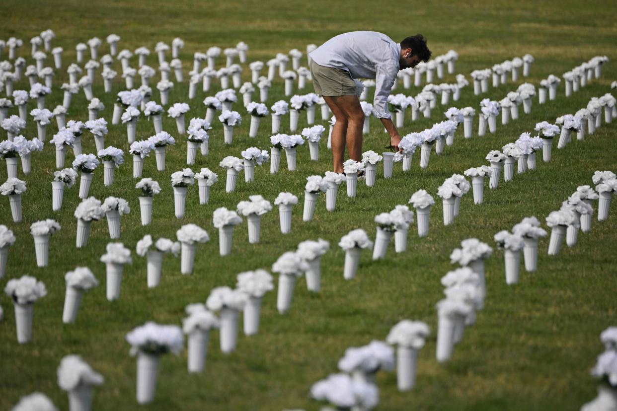 June 7, 2022:  A person adjusts flowers ahead of the opening of the Gun Violence Memorial on the National Mall in Washington, DC. Each vase of flowers in the memorial, set up by the Gabby Giffords Foundation, represents one of the 45,222 Americans who died from gun violence in 2020.