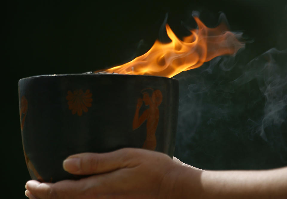 FILE - Greek actress Maria Nafpliotou, playing the role of a high priestess, holds up the Olympic flame lit with a concave mirror near the Temple of Hera in Ancient Olympia, March 24, 2008 where the Olympics were born in 776 B.C. On Tuesday, April 16, 2024 the flame for this summer's Paris Olympics will be lit and be carried through Greece for more than 5,000 kilometers (3,100 miles) before being handed over to French organizers at the Athens site of the first modern Olympics. (AP Photo/Thanassis Stavrakis, File)