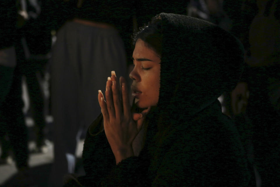 A woman prays during a vigil for the victims of a fire at an immigration detention center that killed dozens in Ciudad Juarez, Mexico, Tuesday, March 28, 2023. According to Mexican President Andres Manuel Lopez Obrador, migrants fearing deportation set mattresses ablaze at the center, starting the fire. (AP Photo/Christian Chavez)