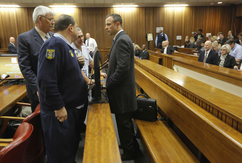 Oscar Pistorius stands inside court for the second day of his trial at the high court in Pretoria, South Africa, Tuesday, March 4, 2014. Pistorius is charged with murder for the shooting death of his girlfriend, Reeva Steenkamp, on Valentine's Day in 2013. (AP Photo/Kim Ludbrook, Pool)