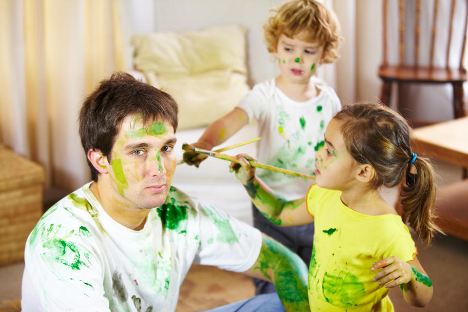 A man is painted green by two messy kids he's babysitting