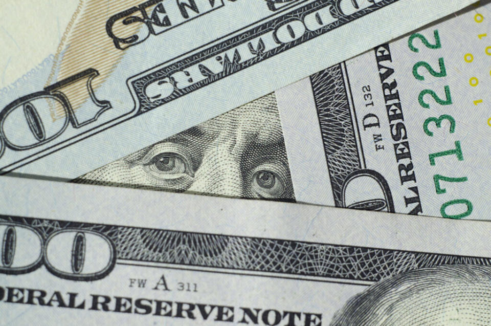 Benjamin Franklin's eyes peer through a trio of $100 bills