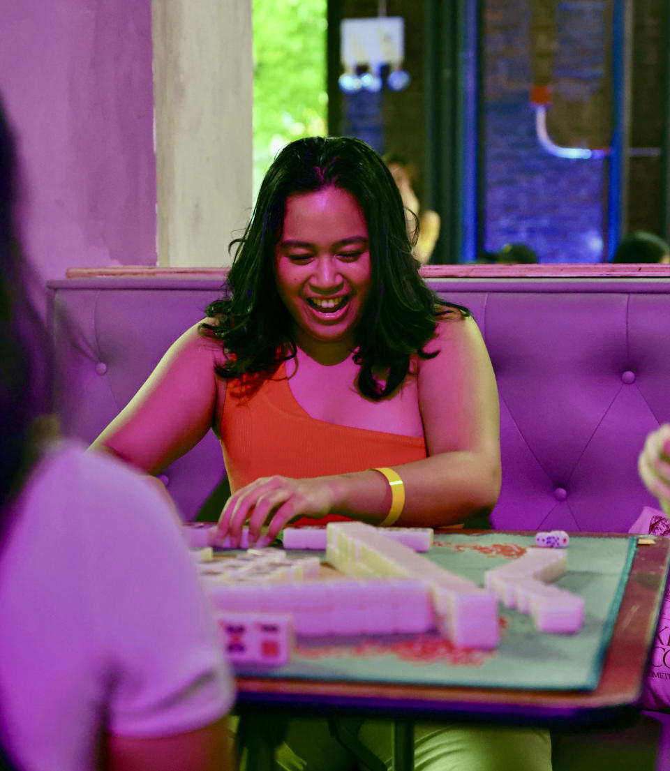 Akiko Barreras shows her winning hand of mahjong to the other players under the purple lights of Hana House. (Jordan Winters)