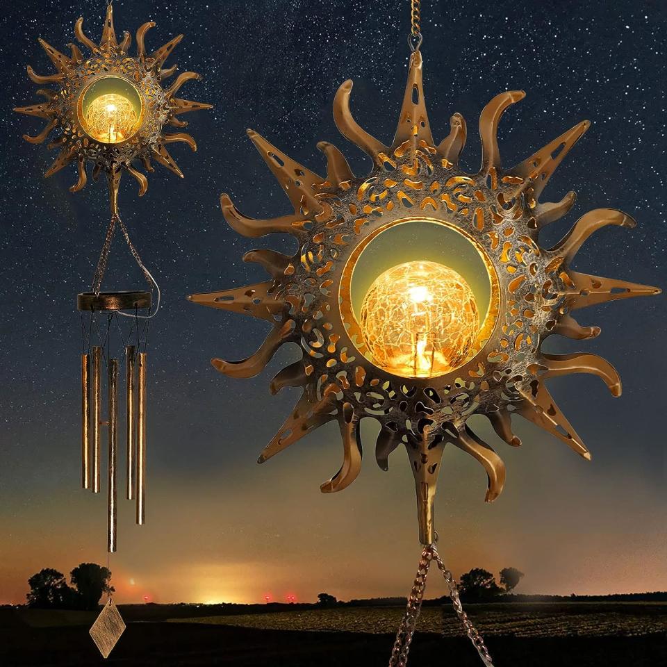 Two sun-shaped wind chimes with built-in lamps hanging in front of a night sky