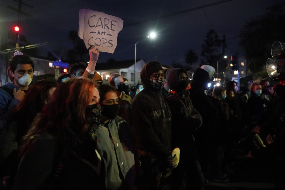 Demonstrators huddle in front of police in the Echo Park section of Los Angeles Thursday, March 25, 2021. Demonstrators gathered Wednesday night to protest the planned temporary closure of a Los Angeles park that would displace a large homeless encampment, which has grown throughout the coronavirus pandemic. (AP Photo/Marcio Jose Sanchez)